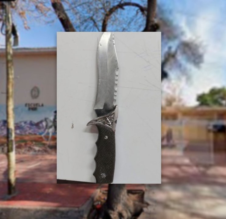 Ilustración de una escuela con un símbolo de seguridad y un círculo rojo de prohibición sobre un objeto punzante.