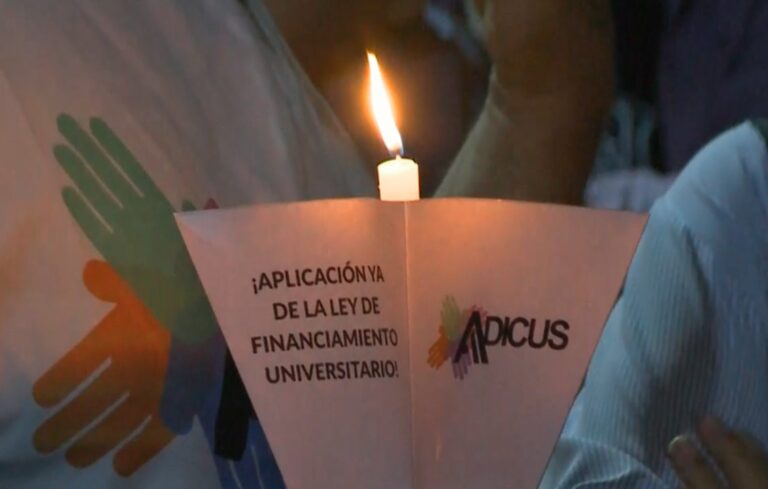 Participantes de la marcha de antorchas frente al edificio de la Escuela de Comercio de la UNSJ, de noche.