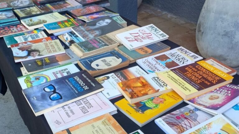 Personas observando y seleccionando libros de un estante durante la actividad de suelta de libros en San Juan.